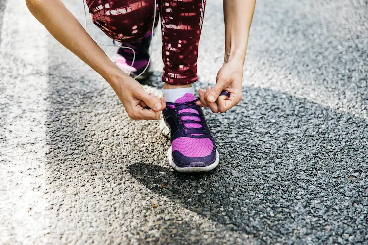 Mujer atándose los cordones después de elegir zapatillas para correr