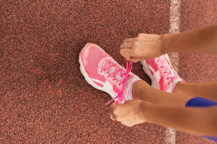Mujer atándose los cordones de sus zapatillas para hacer running